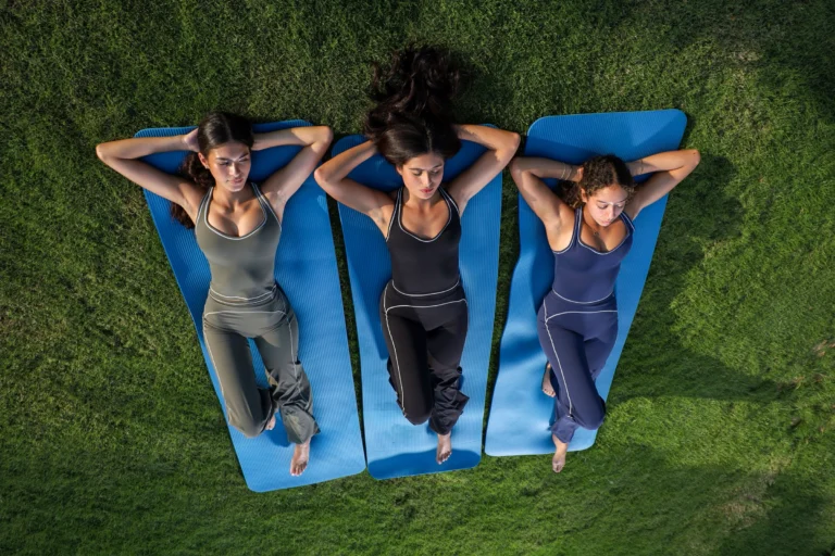 Three women relaxing on yoga mats in DLiners sets.